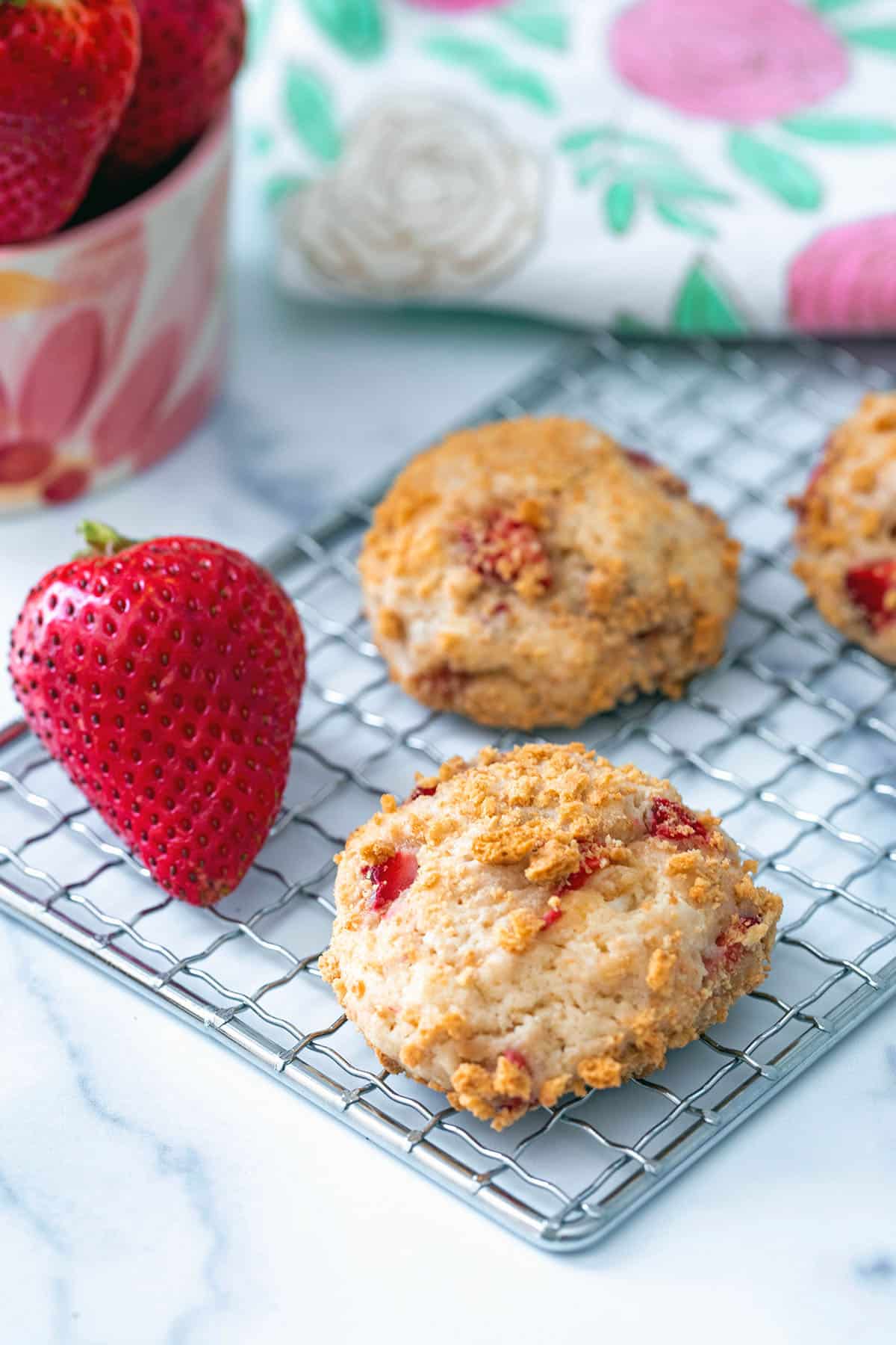 Strawberry cheesecake cookies with fresh strawberry on baking rack.