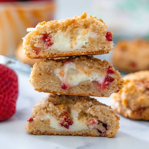 Closeup view of strawberry cheesecake cookies stacked on each other showing cream cheese middles.