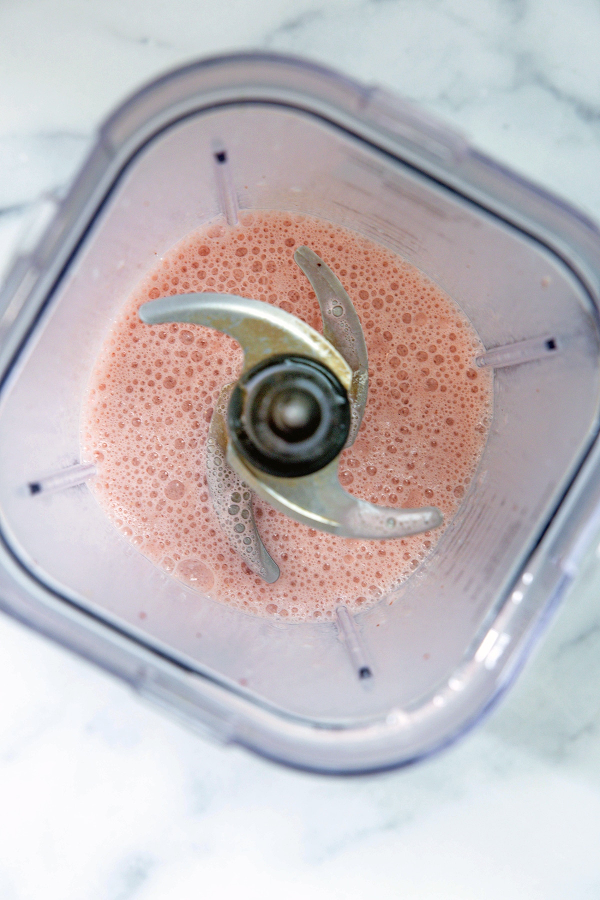 Overhead view of strawberry cheesecake frappuccino blended together in blender.