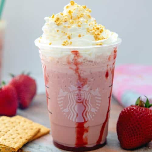 Closeup view of a Strawberry Cheesecake Frappuccino with strawberries and graham crackers.