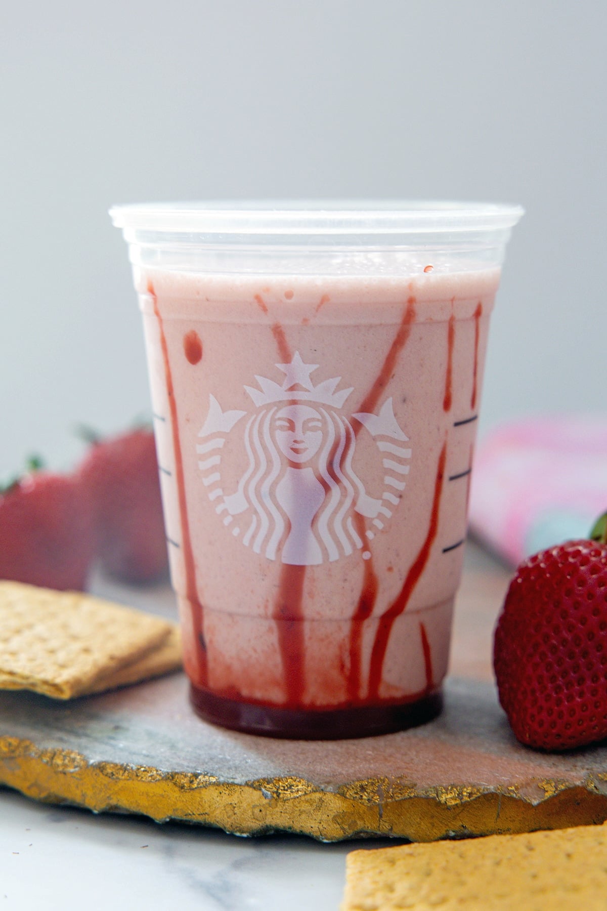 Head-on view of strawberry cheesecake frappuccino poured into a cup with strawberry puree swirls on the sides.