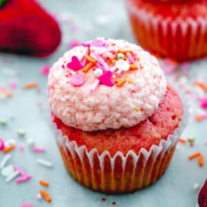 Closeup view of a strawberry cupcake with strawberry frosting sprinkles on top.