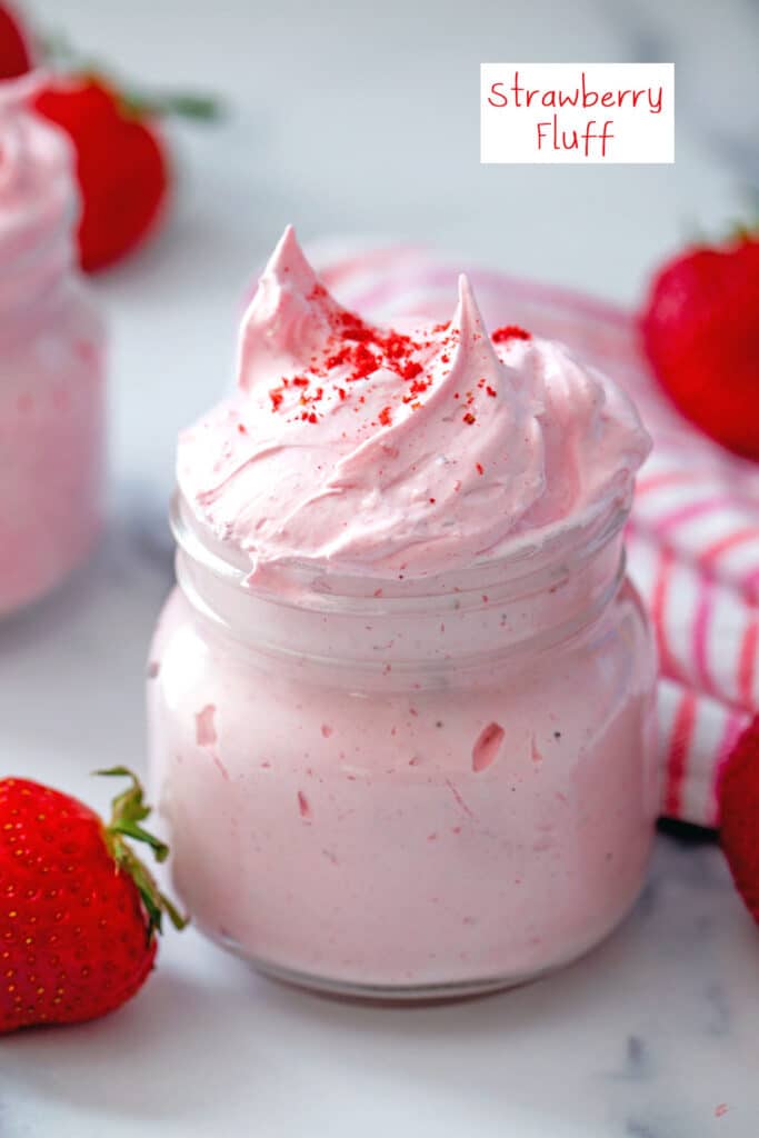 Small mason jar of strawberry fluff with whole strawberries in background and recipe title at top.