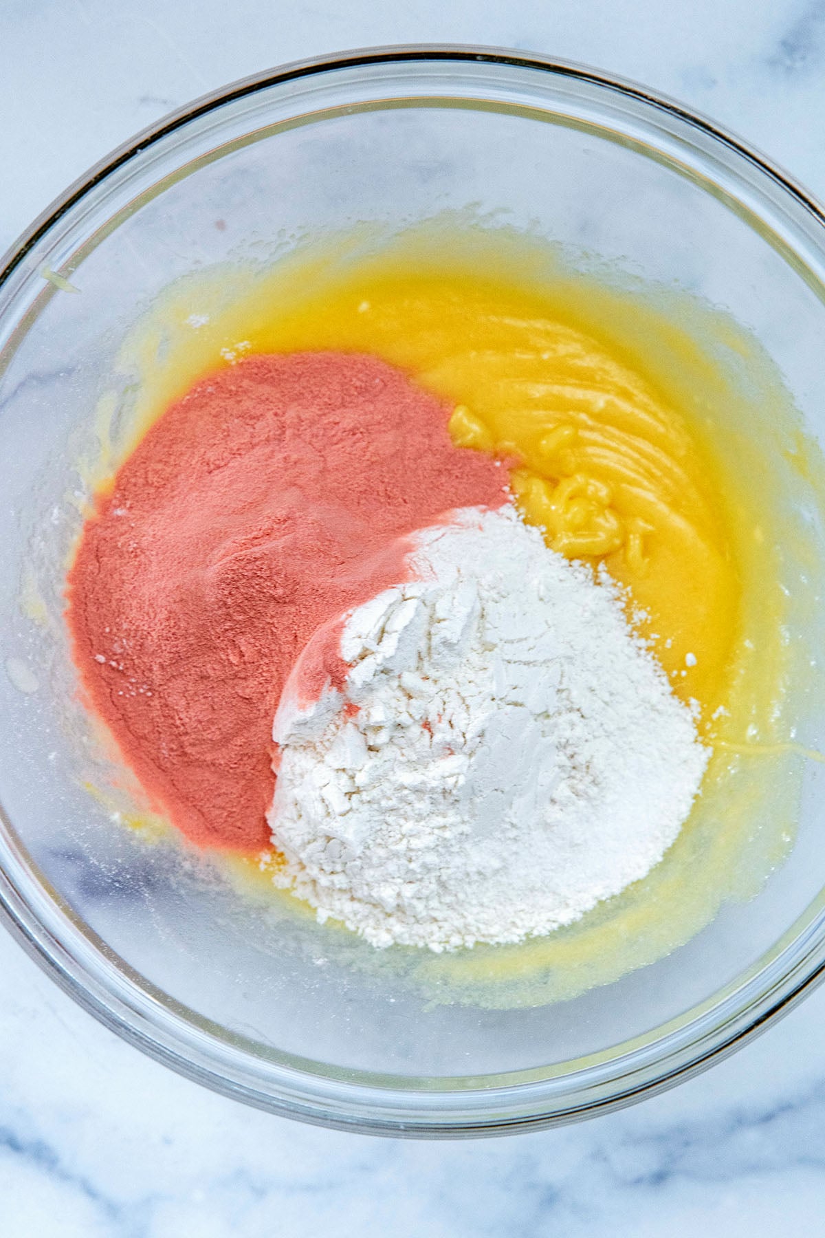 Wet ingredients, dry ingredients, and freeze-dried strawberry powder in a mixing bowl.