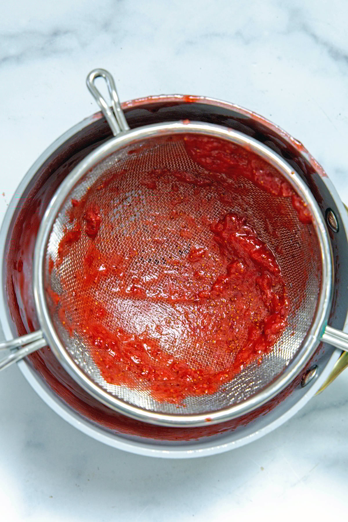 Strawberry puree being strained into bowl.