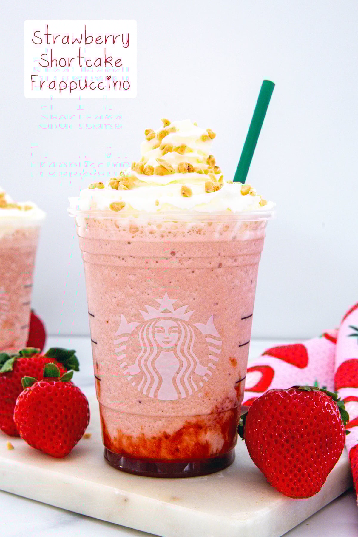 Head-on view of a Strawberry Shortcake Frappuccino with whipped cream and toffee bits with recipe title at top.