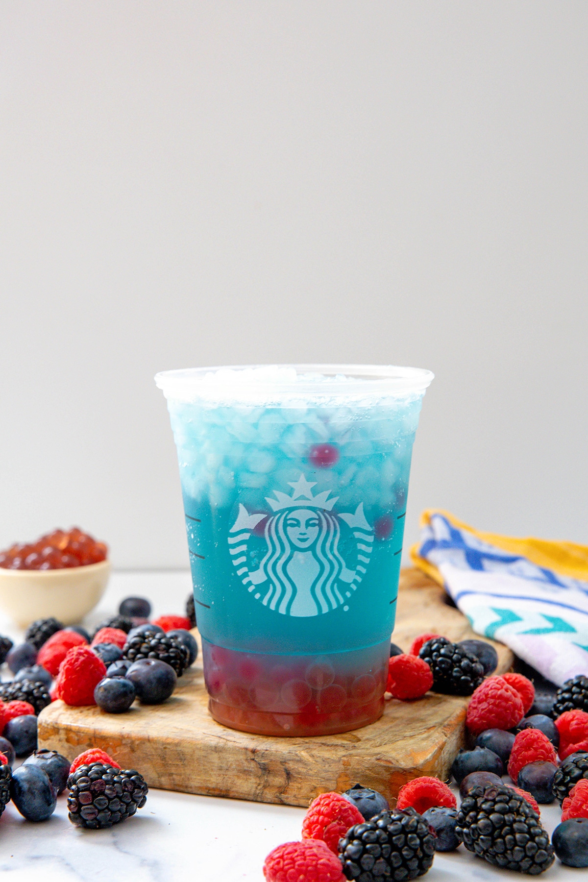 Head-on view of a Summer-Berry Refresher with berries all around an raspberry pearls in background.