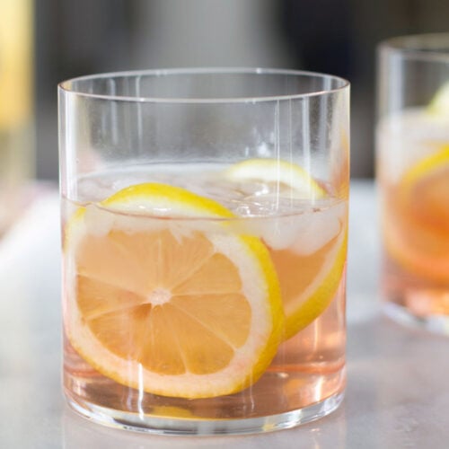 Closeup head-on view of a summer rosé spritzer with lemon rounds in a rocks glass.