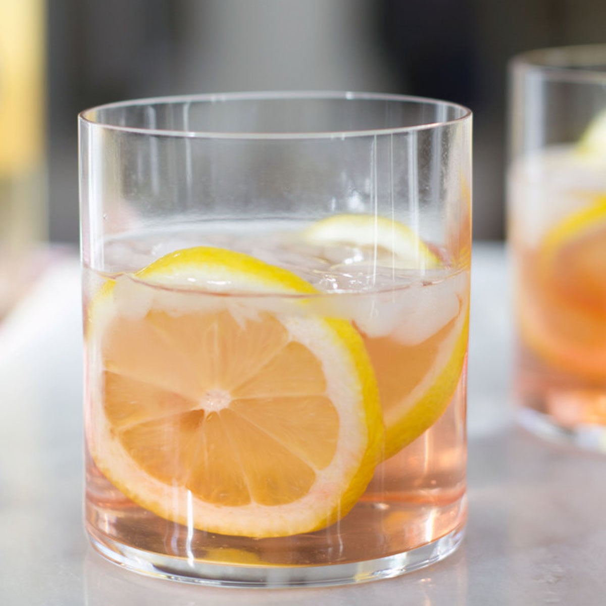 Closeup head-on view of a summer rosé spritzer with lemon rounds in a rocks glass.