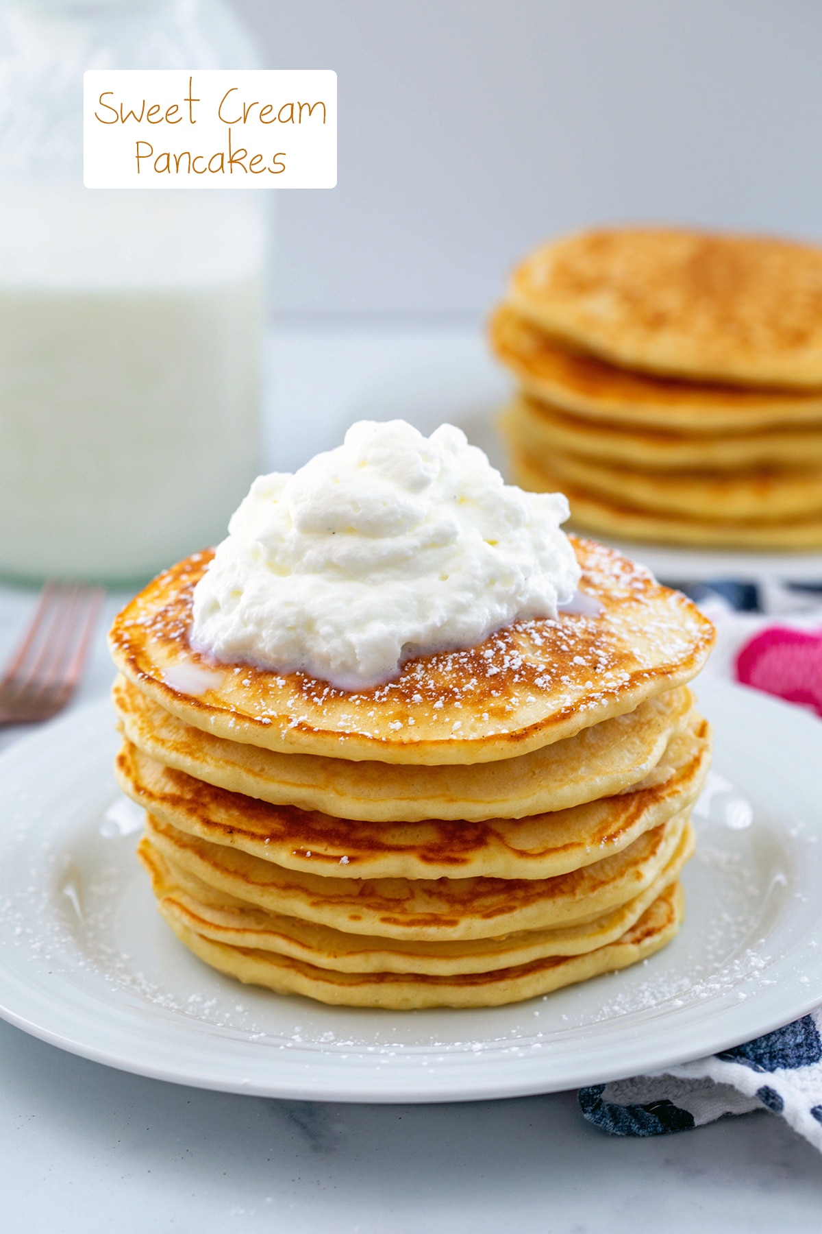 Stack of sweet cream pancakes topped with sweet cream cold foam with recipe title on top.