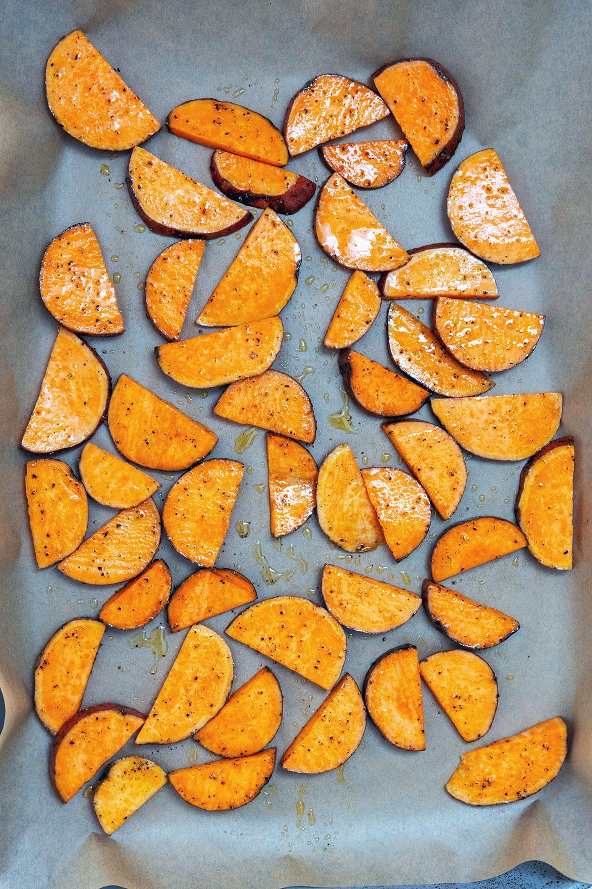 Half moon sweet potatoes on baking sheet.