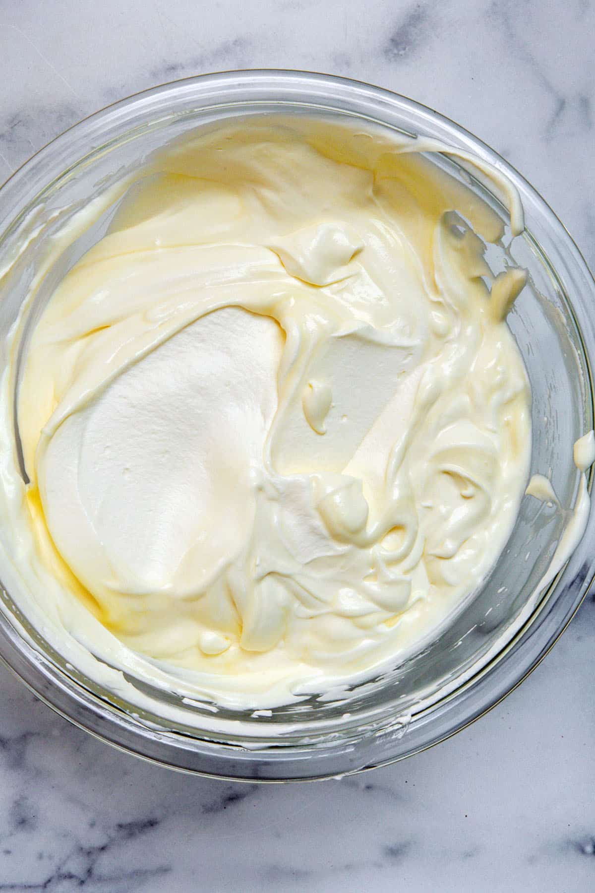 Sweetened condensed milk and whipped cream mixed together in bowl.