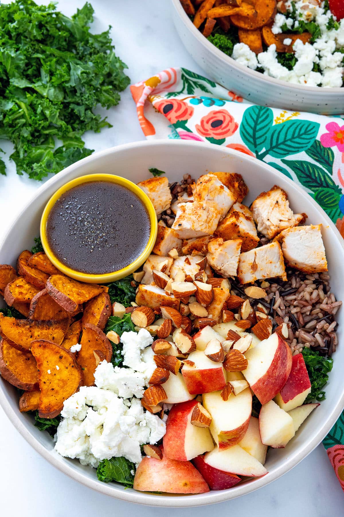 Closeup view of a Sweetgreen Harvest Bowl with little bowl of dressing and kale on the side.