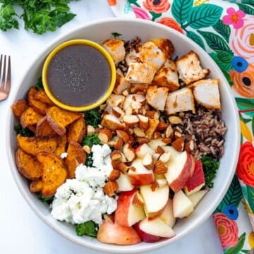 Overhead closeup view of a Sweetgreen Harvest Bowl with dressing in small bowl.