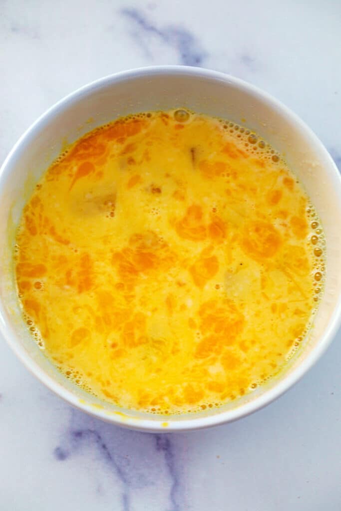 Tempering hot cream/milk in egg yolks in bowl.