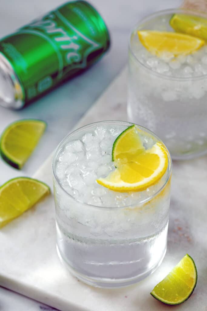 Overhead view of a glass of tequila and Sprite with second glass and can of Sprite in background.