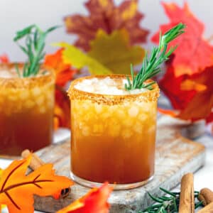 Thanksgiving margarita with rosemary garnish and fall leaves all around.