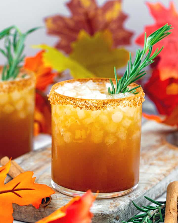 Thanksgiving margarita with rosemary garnish and fall leaves all around.