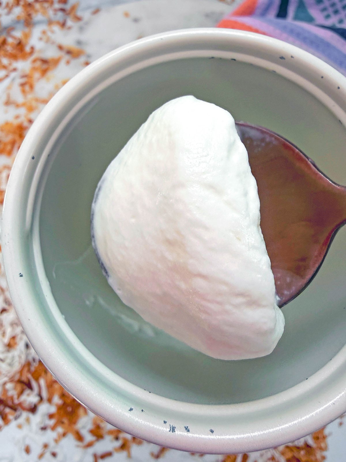 Overhead view of a spoon holding up toasted coconut cream cold brew.