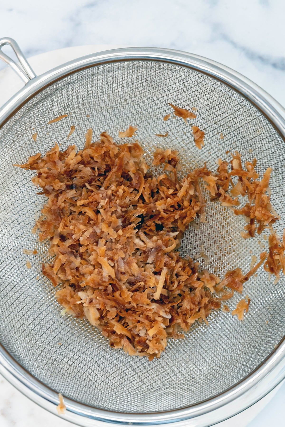 Toasted coconut being strained out of syrup.