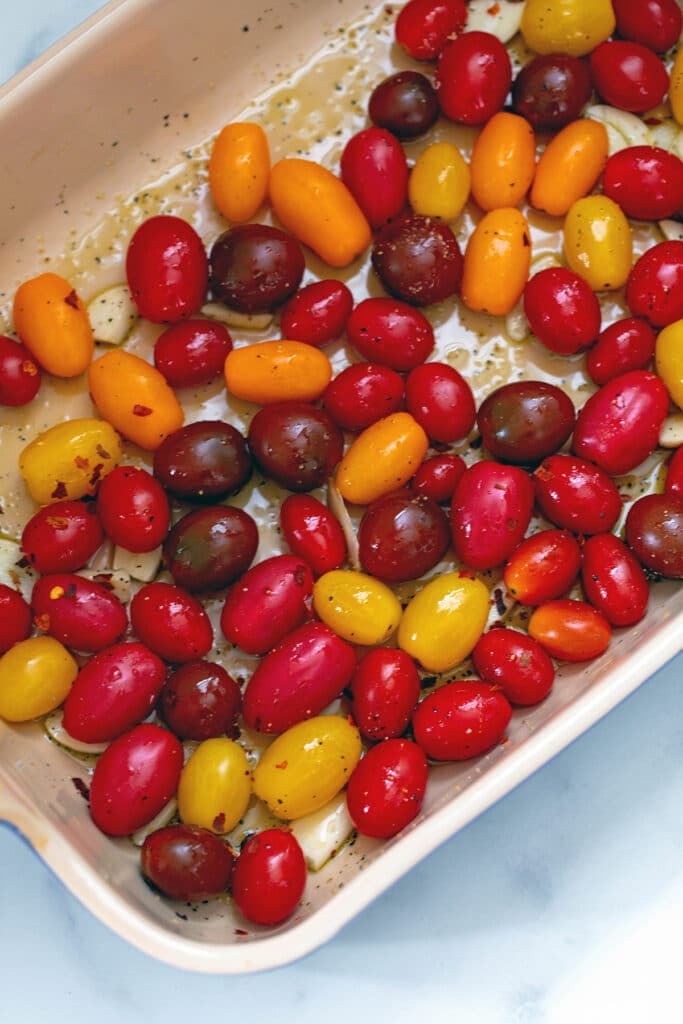 Colorful tomatoes and sliced garlic in a casserole dish.