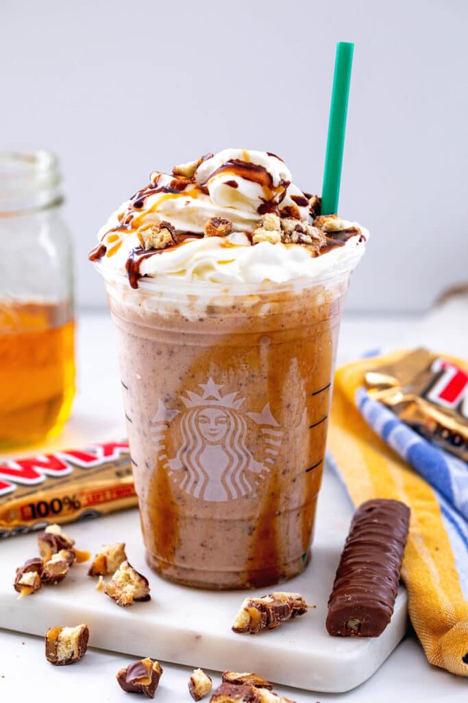 Head-on view of a Twix Frappuccino with whipped cream, caramel, and mocha sauce with Twix bars all around.