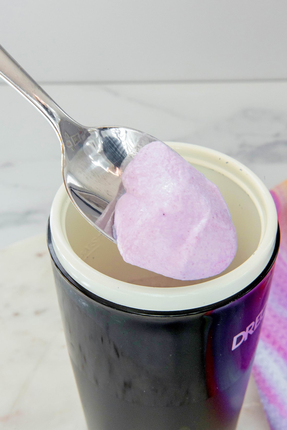 Purple ube coconut cold foam on a spoon.