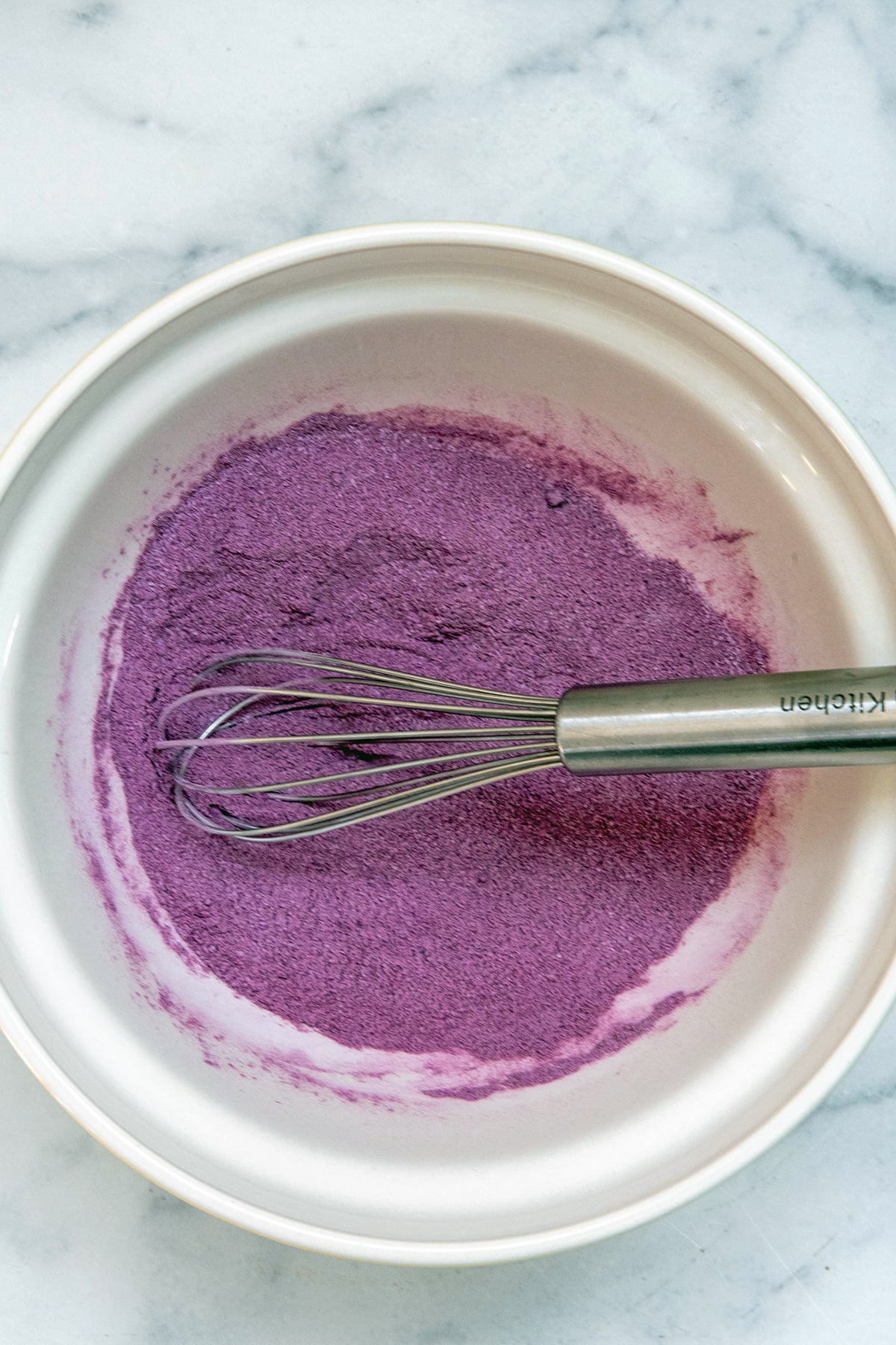 Purple Ube powder mixed with sugar in a bowl with wisk.