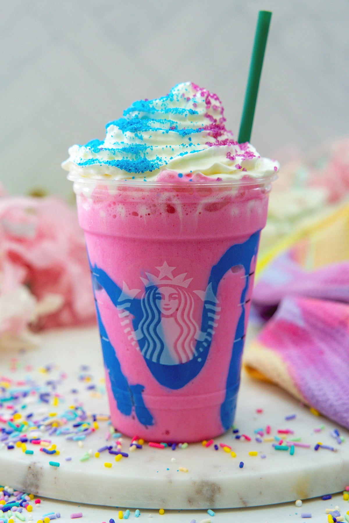Head-on view of a Unicorn Frappuccino with whipped cream and green straw.