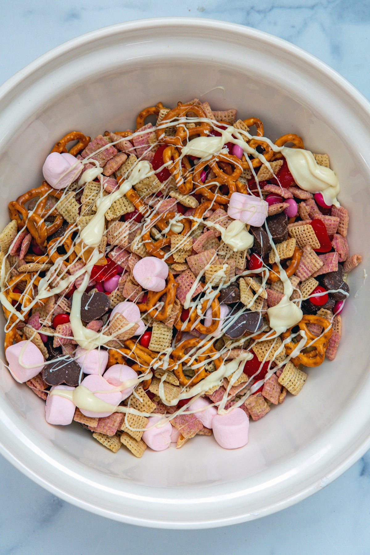 Valentine snack mix in bowl drizzled with melted white chocolate.