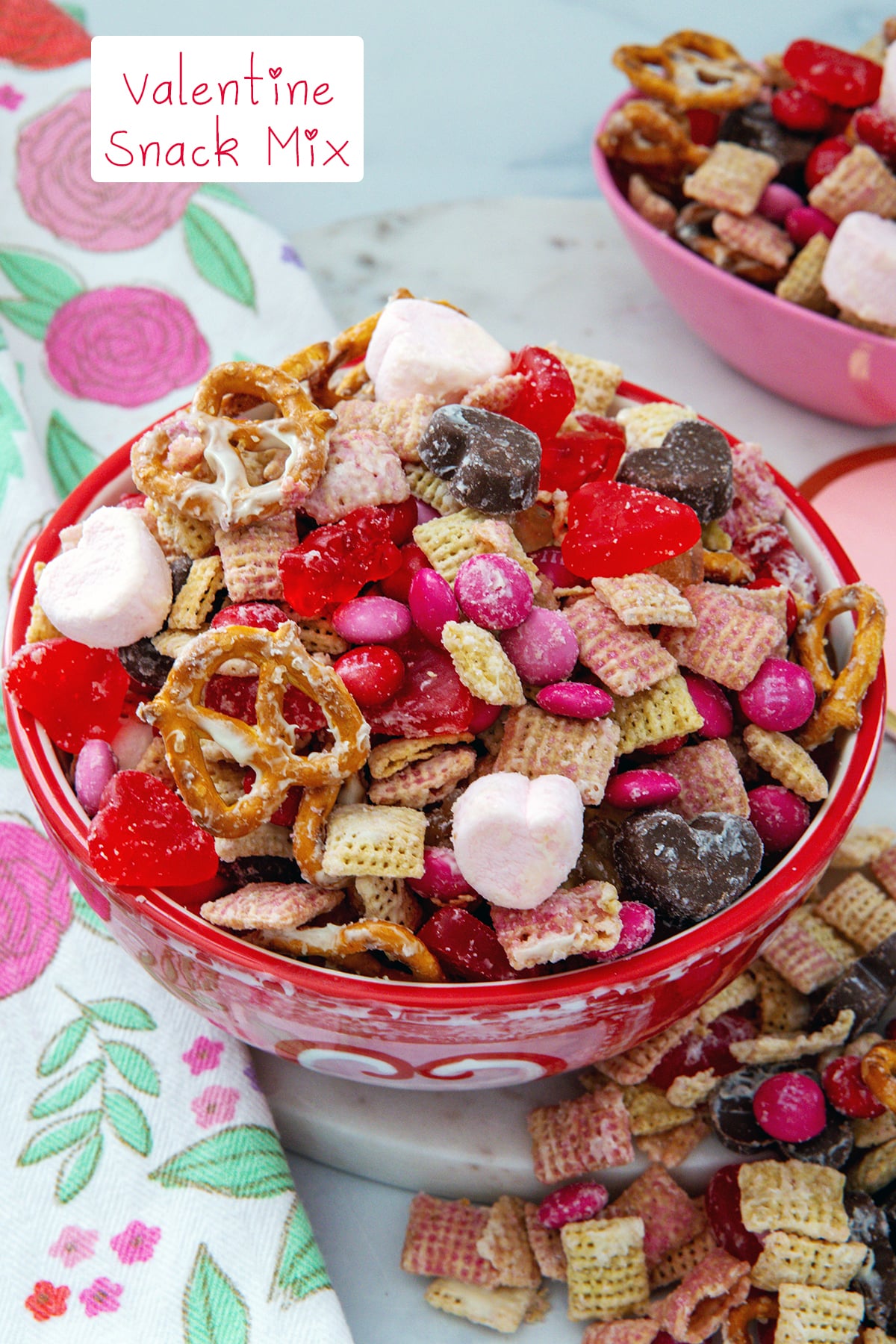 Overhead view of a bowl of Valentine snack mix with pretzels, candy, heart marshmallows, and more with recipe title at top.
