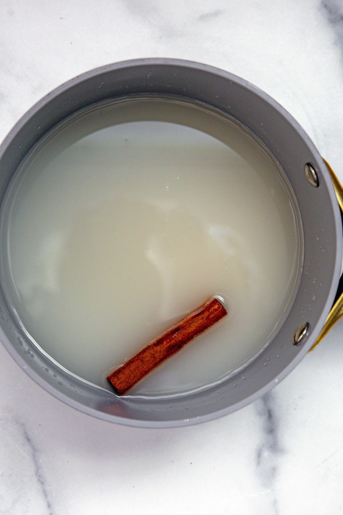 Water, sugar, and cinnamon stick in saucepan.
