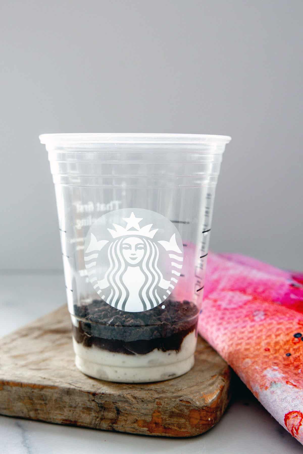 Head-on view of Starbucks cup with whipped cream and mocha sauce on the bottom.