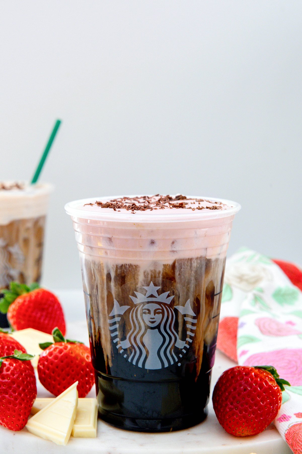 Head-on view of a White Chocolate Strawberry Cream Cold Brew with strawberries and white chocolate bars.