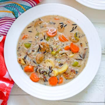 Closeup view of a bowl of wild rice and chicken sausage stew with carrots, parsnips, and more.