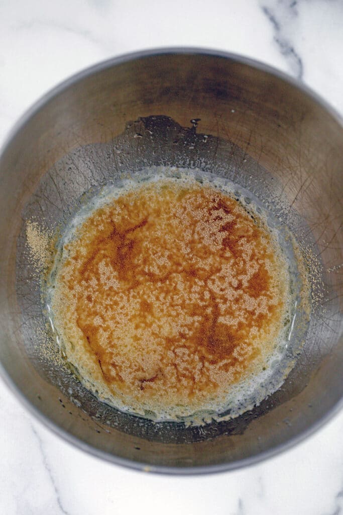 milk and oil in bowl with yeast sprinkled on top.
